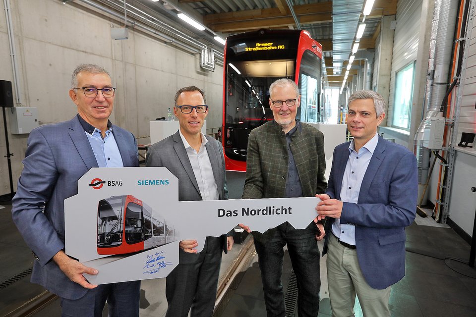 BSAG Nordlicht zeigt die symbolische Schlüsselübergabe und (v.l.) Dr. Frank Hoffmann (Head of Engineering bei Siemens Mobility Rolling Stock), Thorsten Harder (Technischer Vorstand der BSAG), Staatsrat Dr. Ralph Baumheier (Aufsichtsratsvorsitzender der BSAG) und Torsten Frahm (Leiter Center Fahrzeuge)